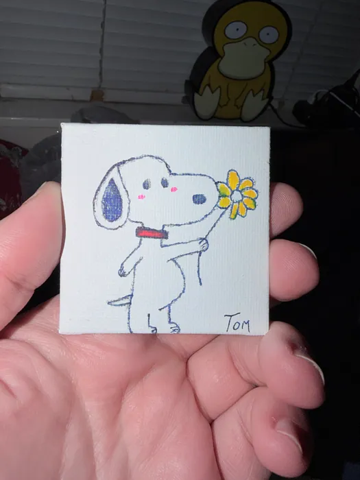 A tiny Snoopy holding a yellow flower on a small canvas.