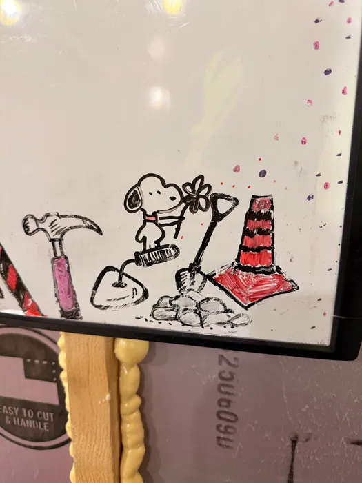 Snoopy near construction tools and a traffic cone.