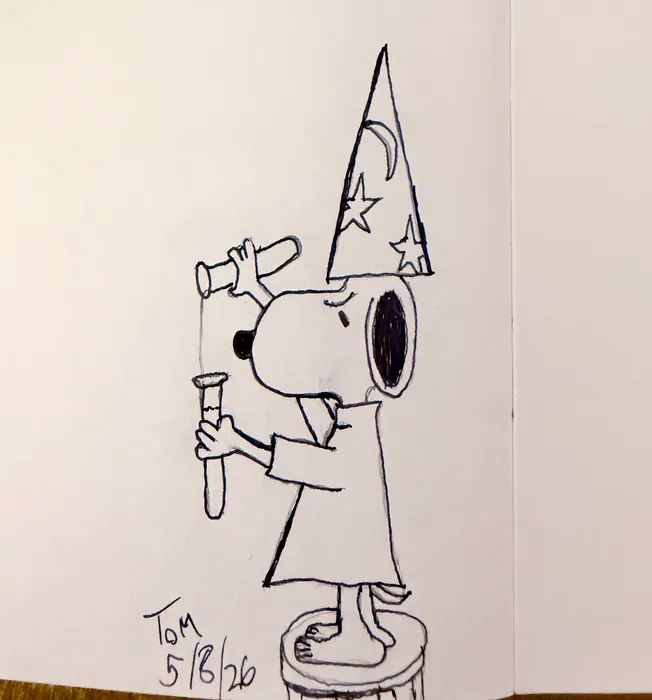 Snoopy dressed as a wizard with a pointed hat and wand.