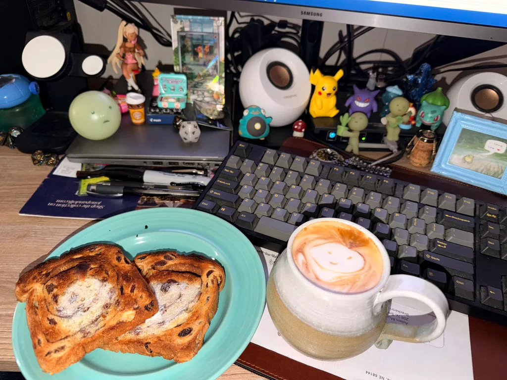 A latte with a smiling face beside breakfast and collectibles.