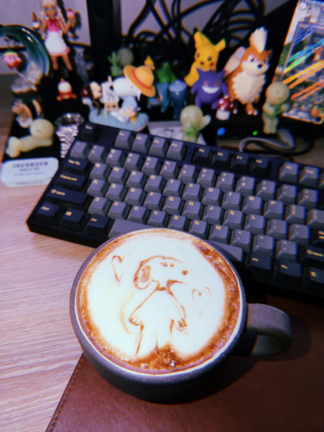 A Snoopy drawing with a flower and heart in latte foam, photographed in front of a keyboard.