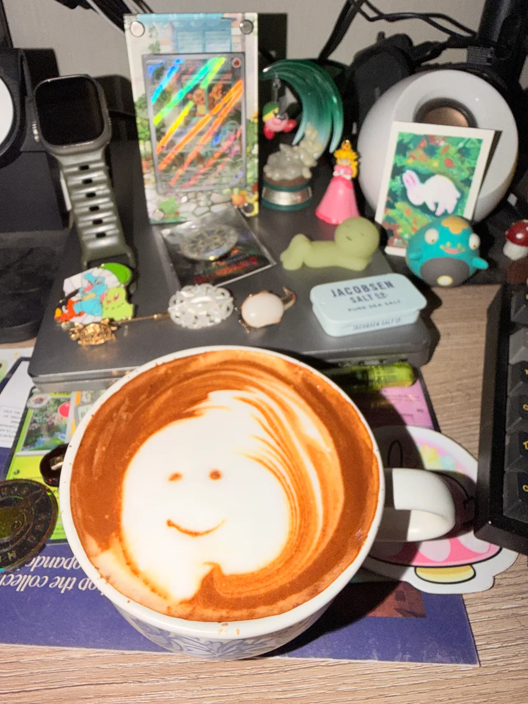 A small smiling face in the foam of a white latte cup on a desk.