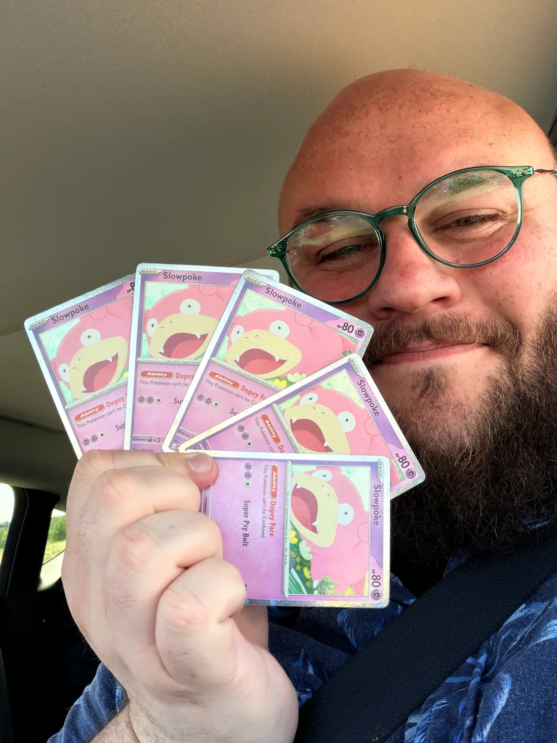 Tom holding a fan of five pink Slowpoke cards with the Dopey Face Ability.